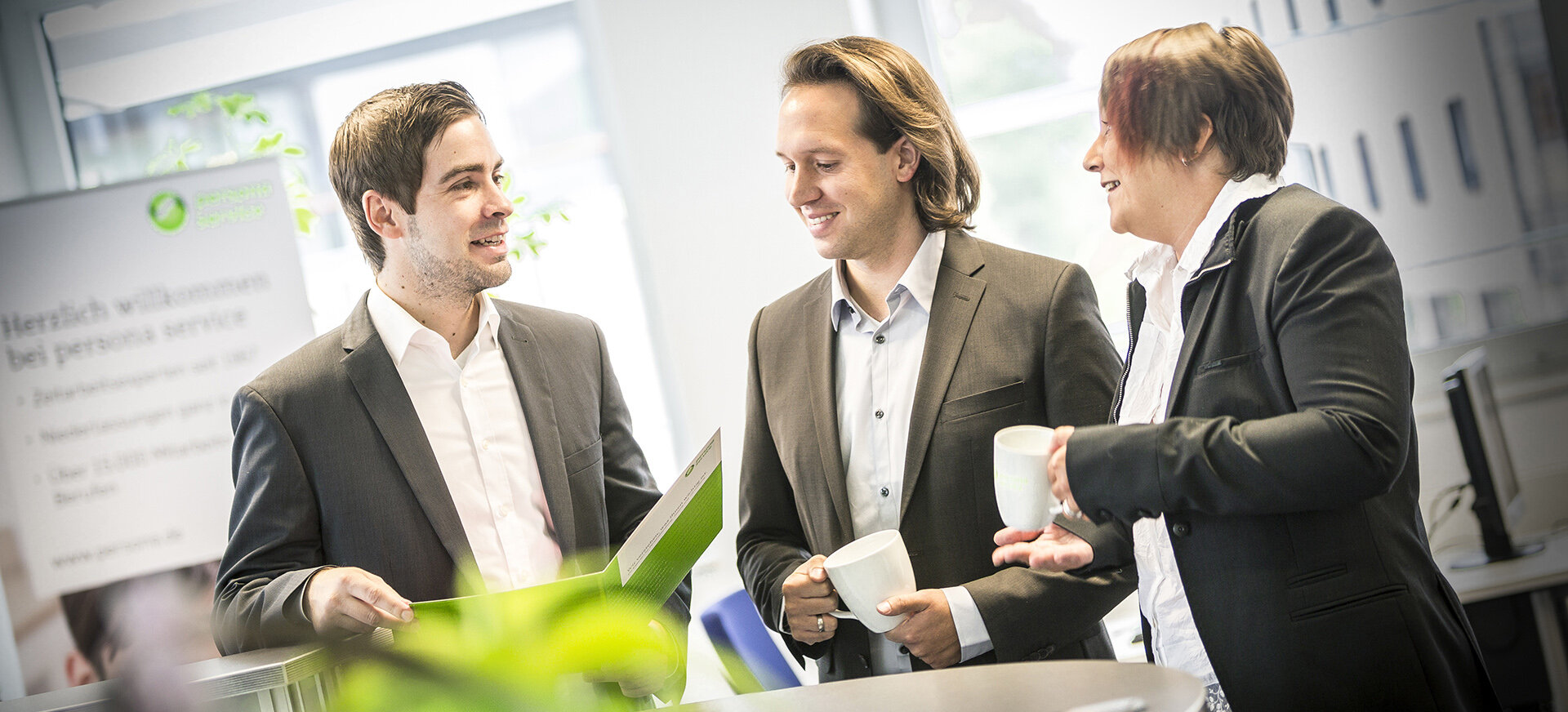 Symbolbild Initiativbewerbung: drei Mitarbeiter unterhalten sich im Büro bei einem Kaffee